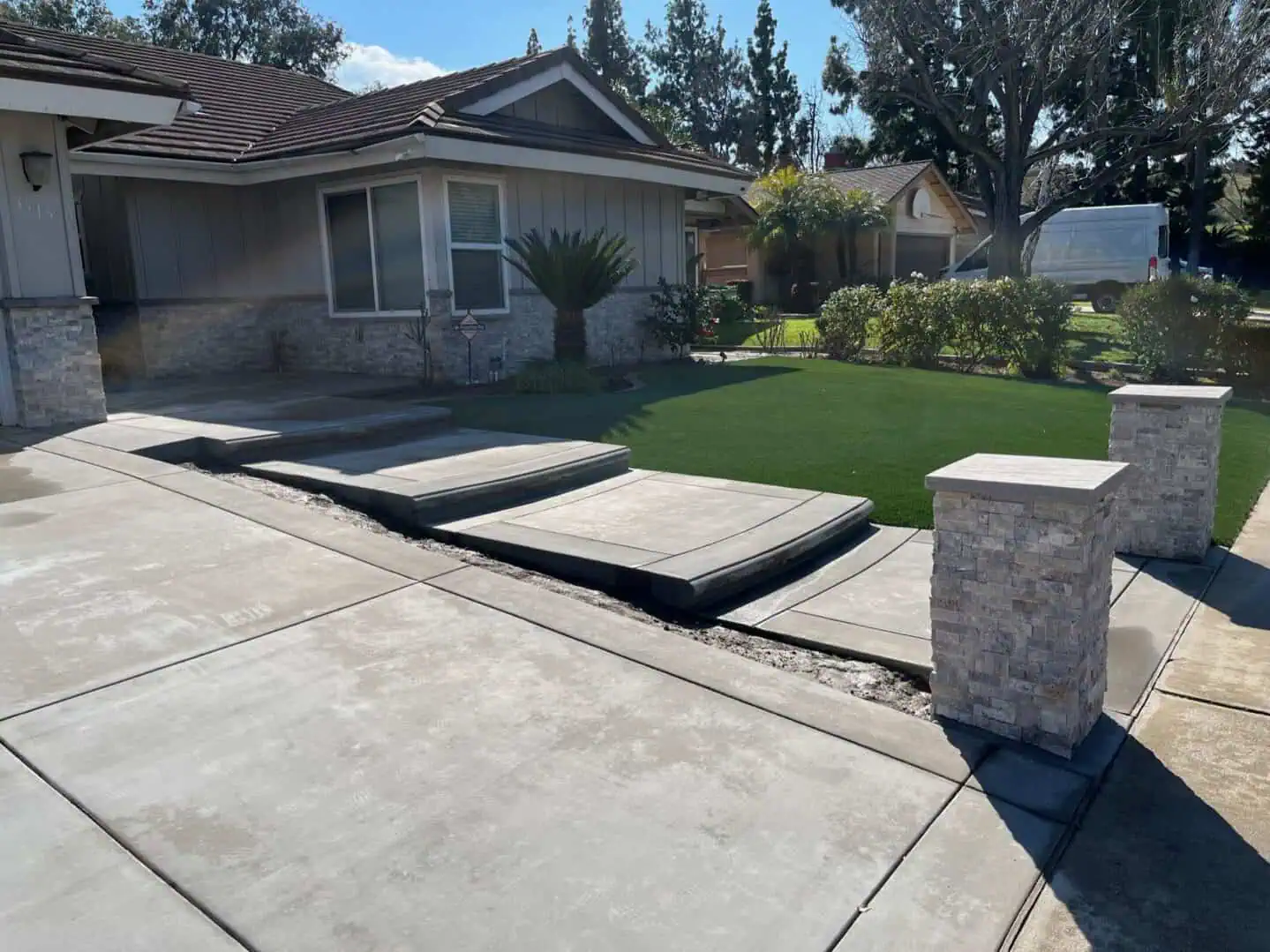 A driveway with concrete steps and grass.