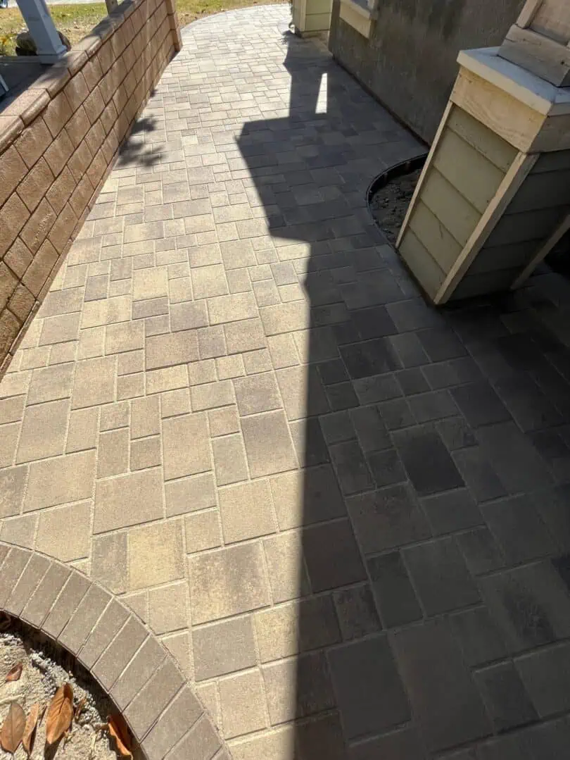 A brick walkway with a bench and wall in the background.