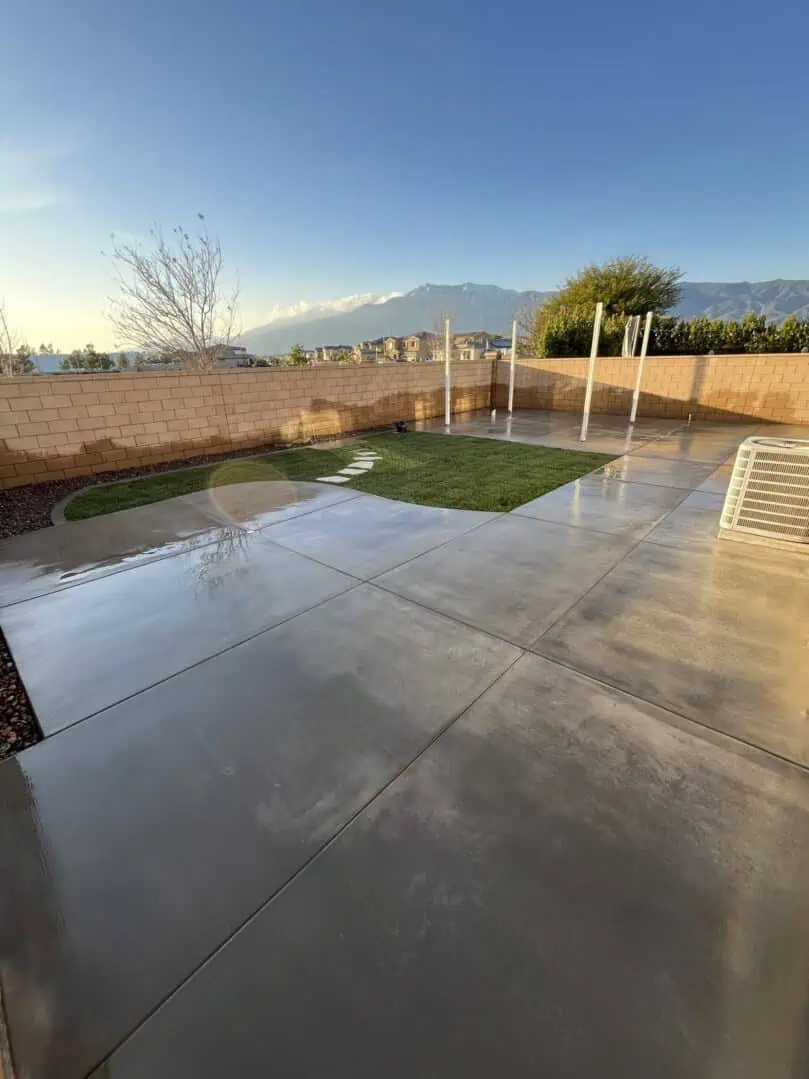 A patio with grass and a fence in the background.