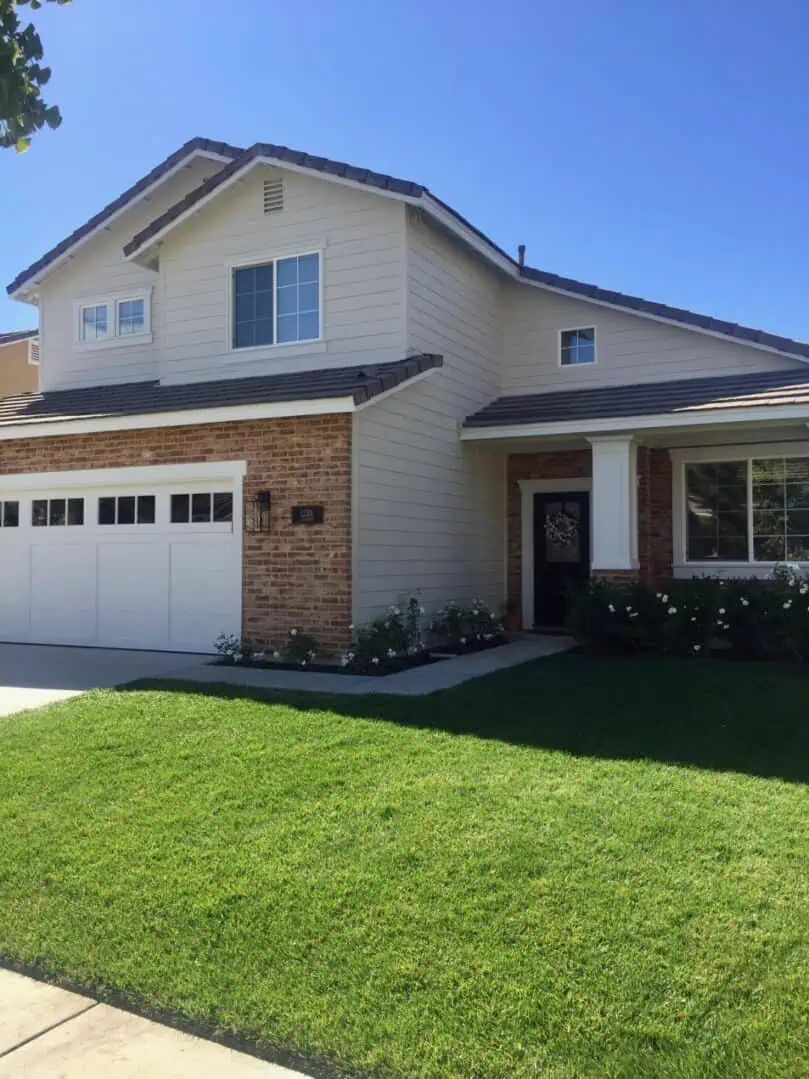 A house with grass and two cars parked in front of it.