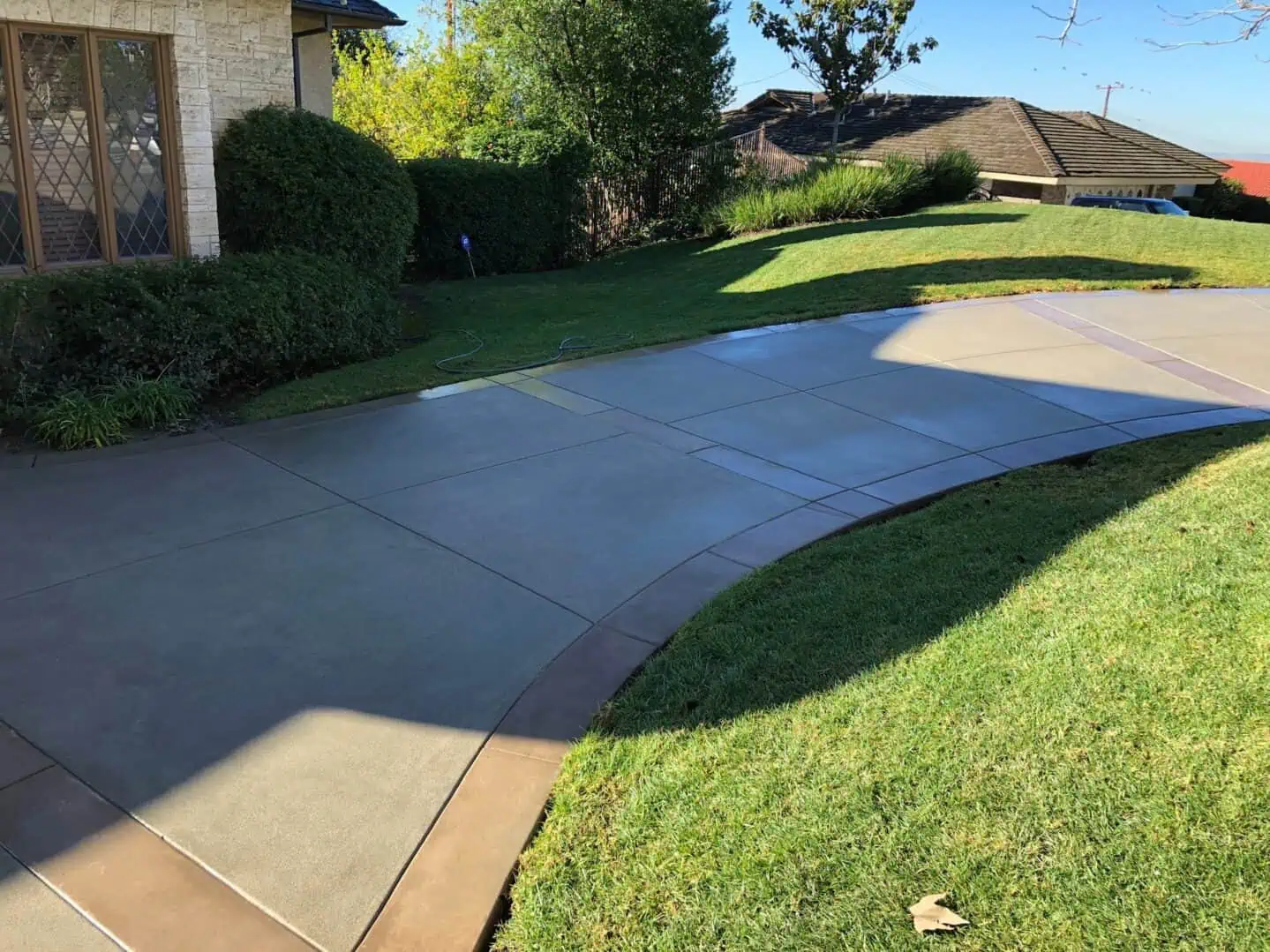 A driveway with grass and bushes in the background.