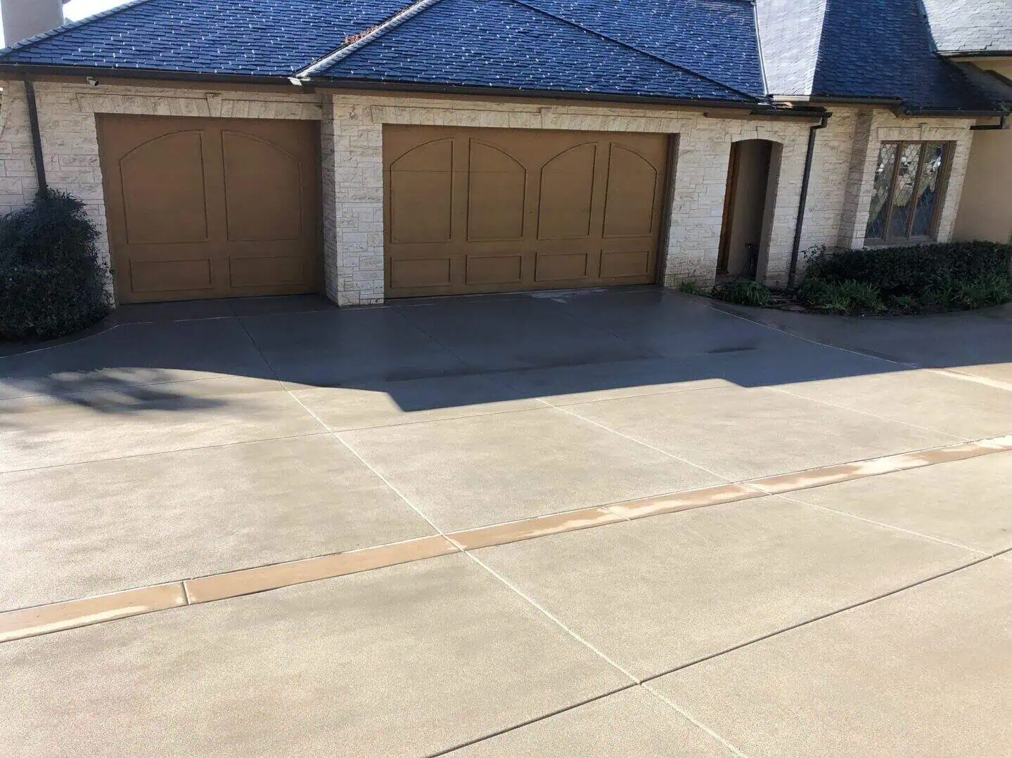 A driveway with two garage doors and a blue roof.