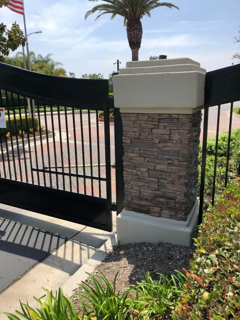 A brick pillar is on the side of a gate.