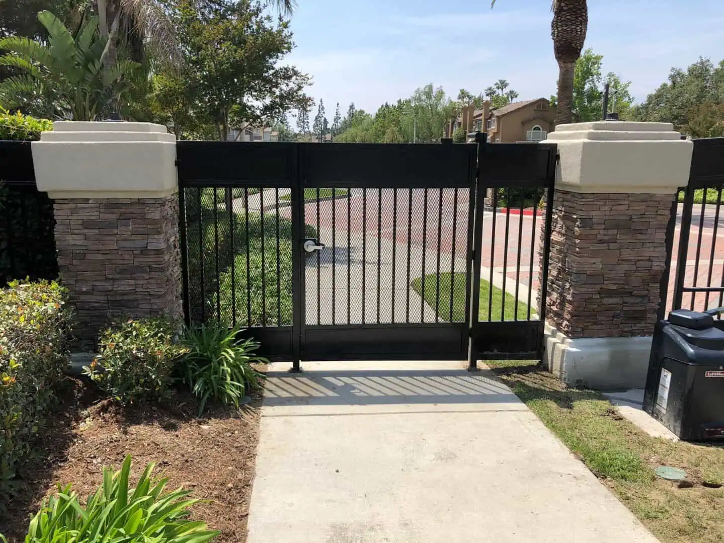 A gated driveway with a metal gate and brick wall.