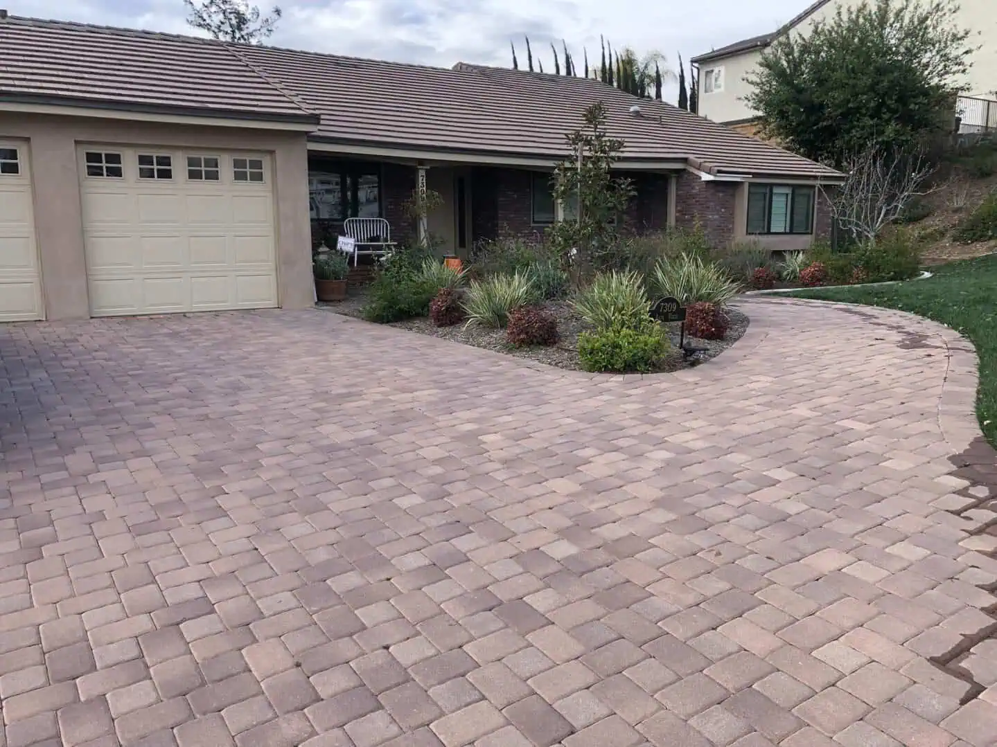 A driveway with a flower bed and garage door.