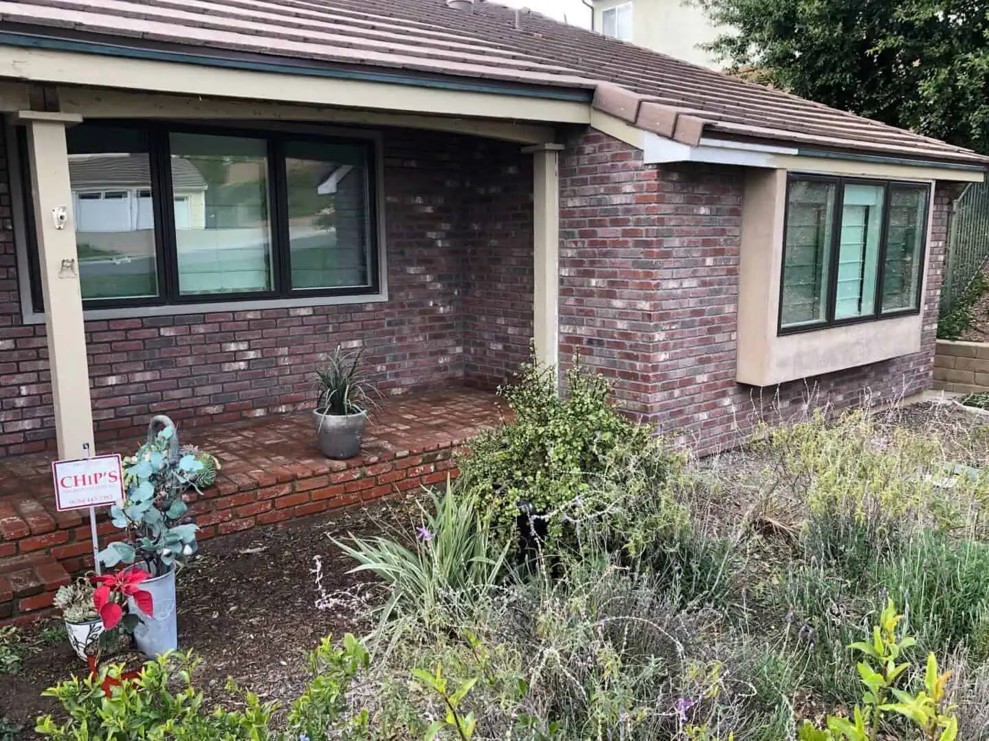 A brick house with plants and bushes outside of it.