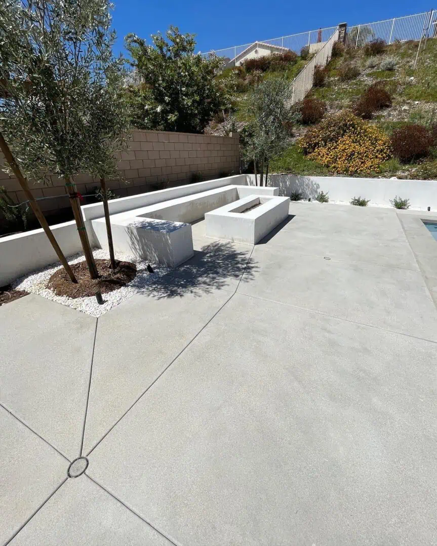 A concrete patio with trees and bushes in the background.