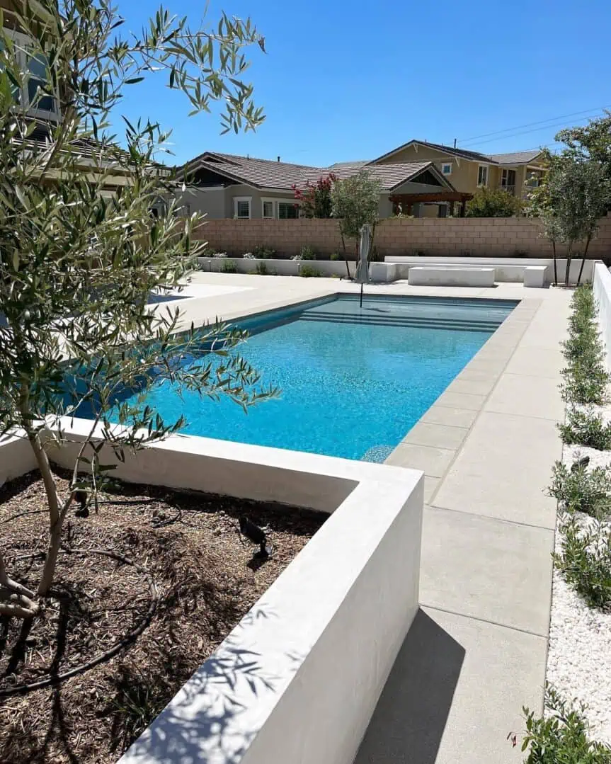 A pool with a large white wall and some trees