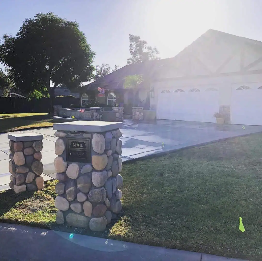 A driveway with a mailbox and stone pillars.