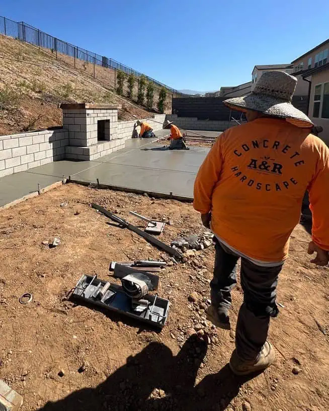 A person in an orange jacket standing on top of a dirt field.