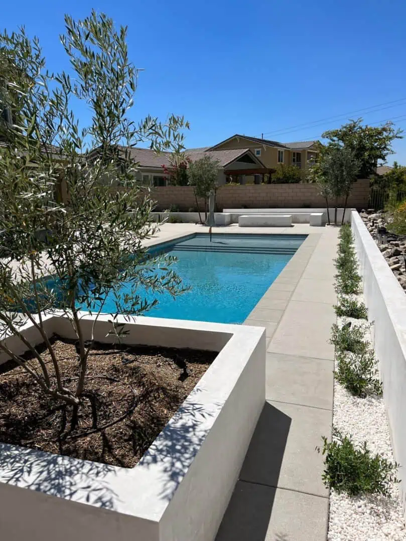 A pool with a large white wall and some trees
