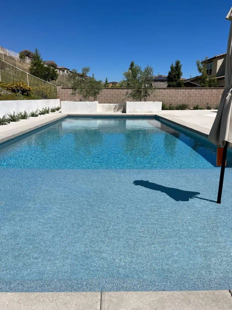 A pool with an umbrella and some bushes