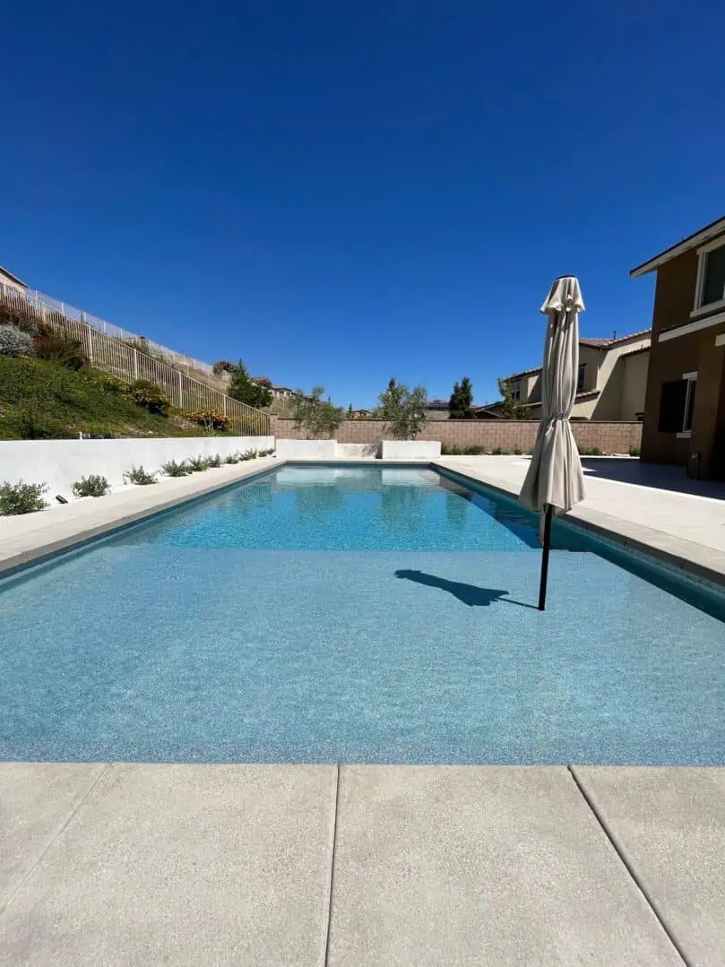 A pool with an umbrella in the middle of it.