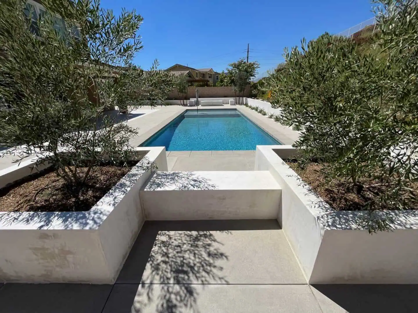 A pool with an elevated deck and a stone wall.