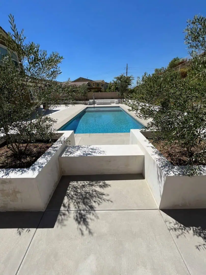 A pool with trees in the background and a house
