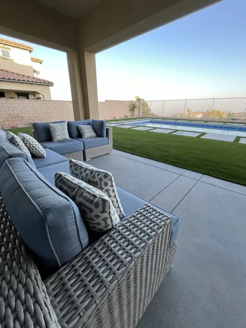 A patio with a couch and chairs next to the pool.