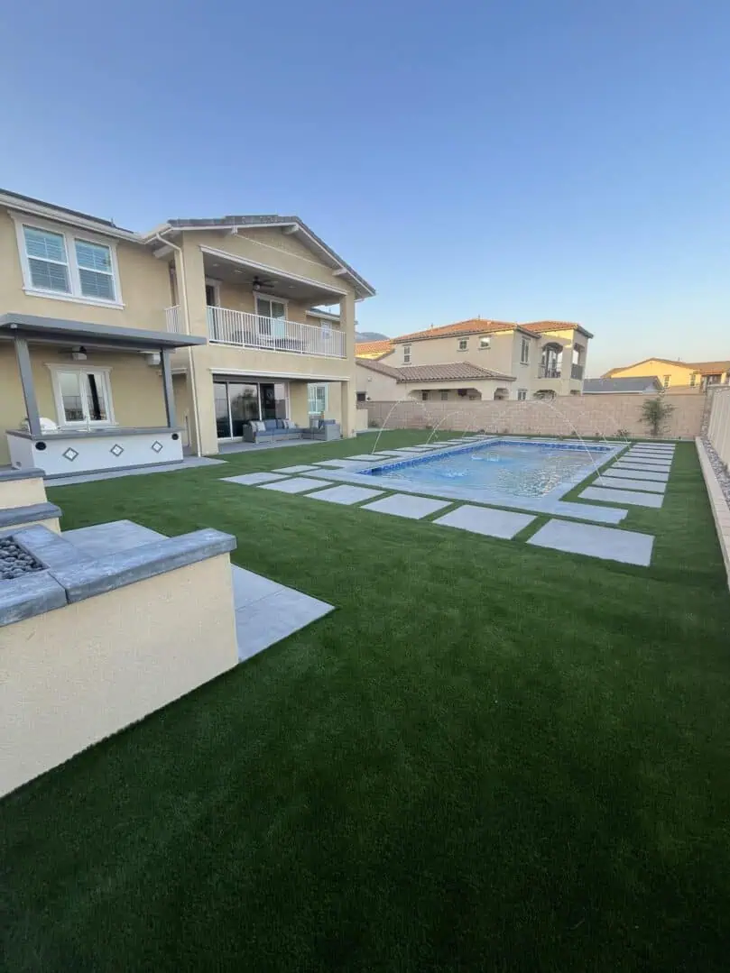 A backyard with a pool and grass.