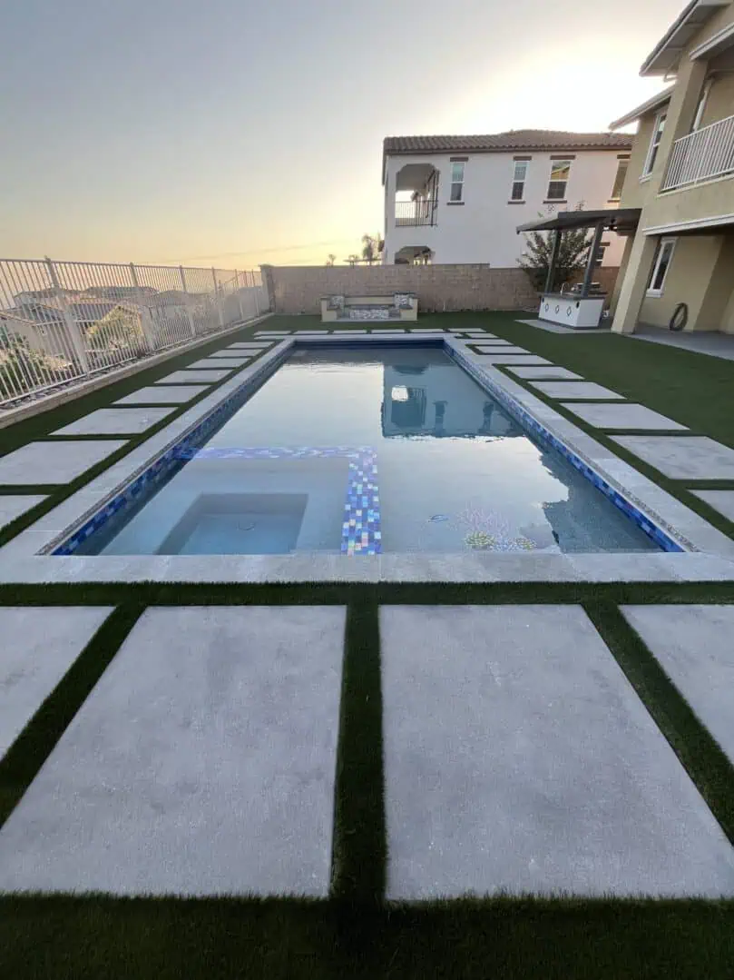 A pool with grass on the ground and an empty swimming pool.