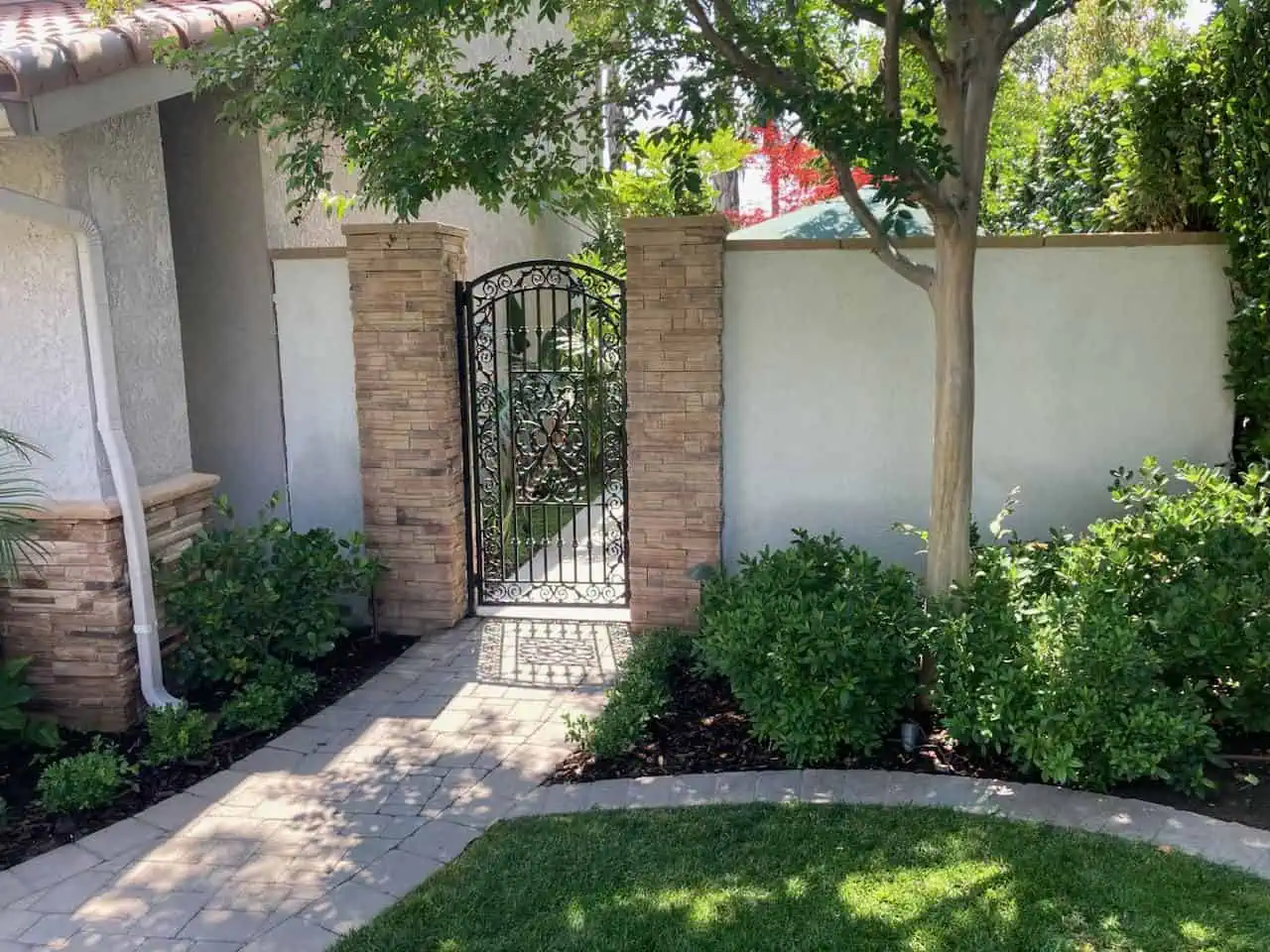 A gated entrance to a home with bushes and trees.