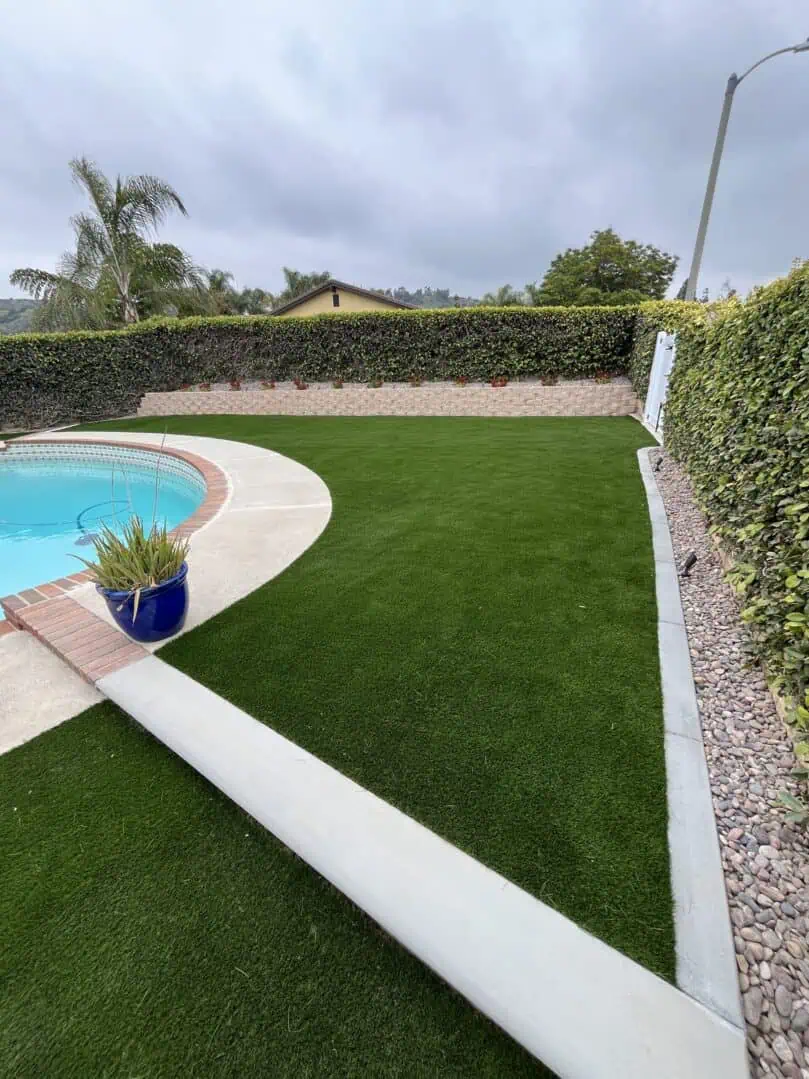A pool with a green lawn and bushes
