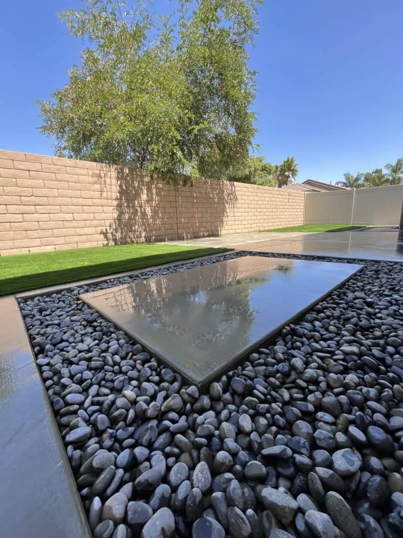 A large glass reflecting pool in the middle of a backyard.