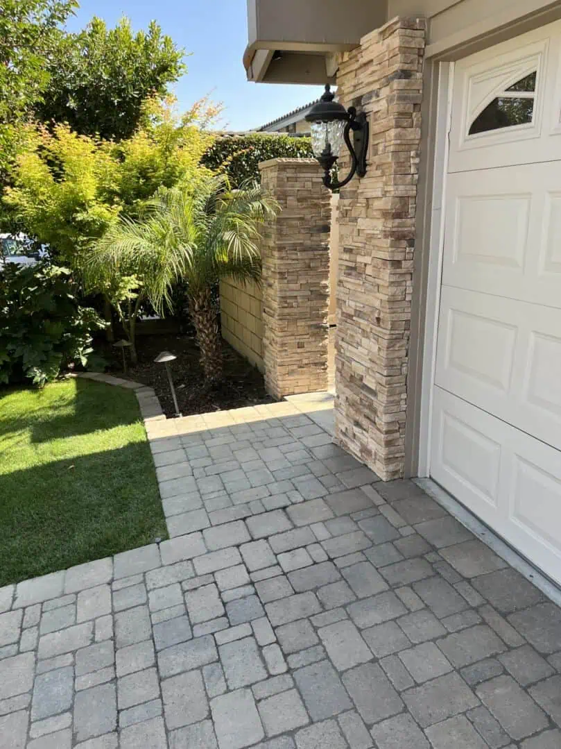 A driveway with a white door and brick wall.