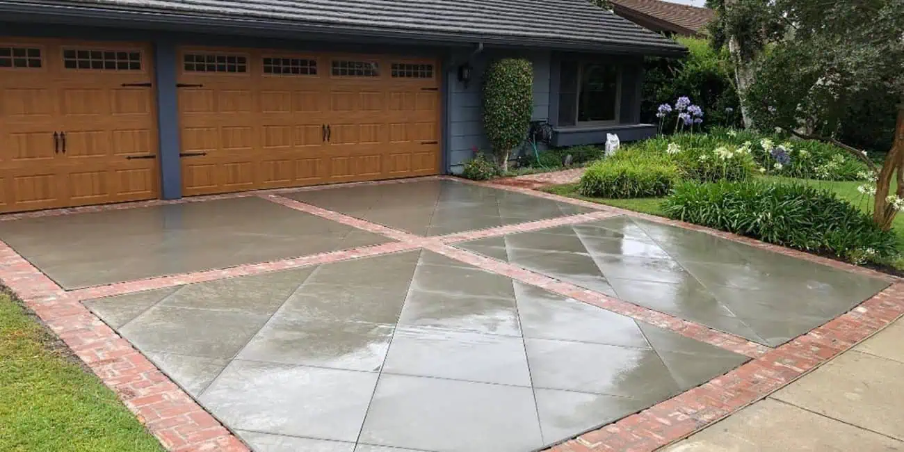 A driveway with a garage door and brick flooring.