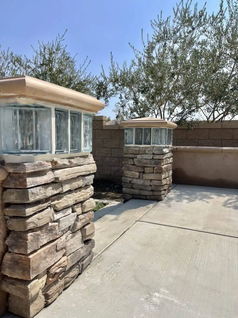 A stone wall with two windows and a concrete floor.