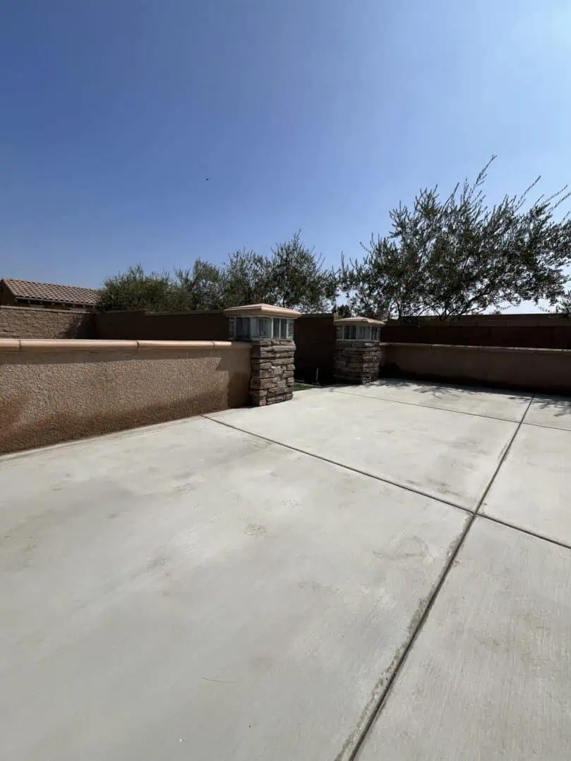 A large concrete driveway with a stone wall.