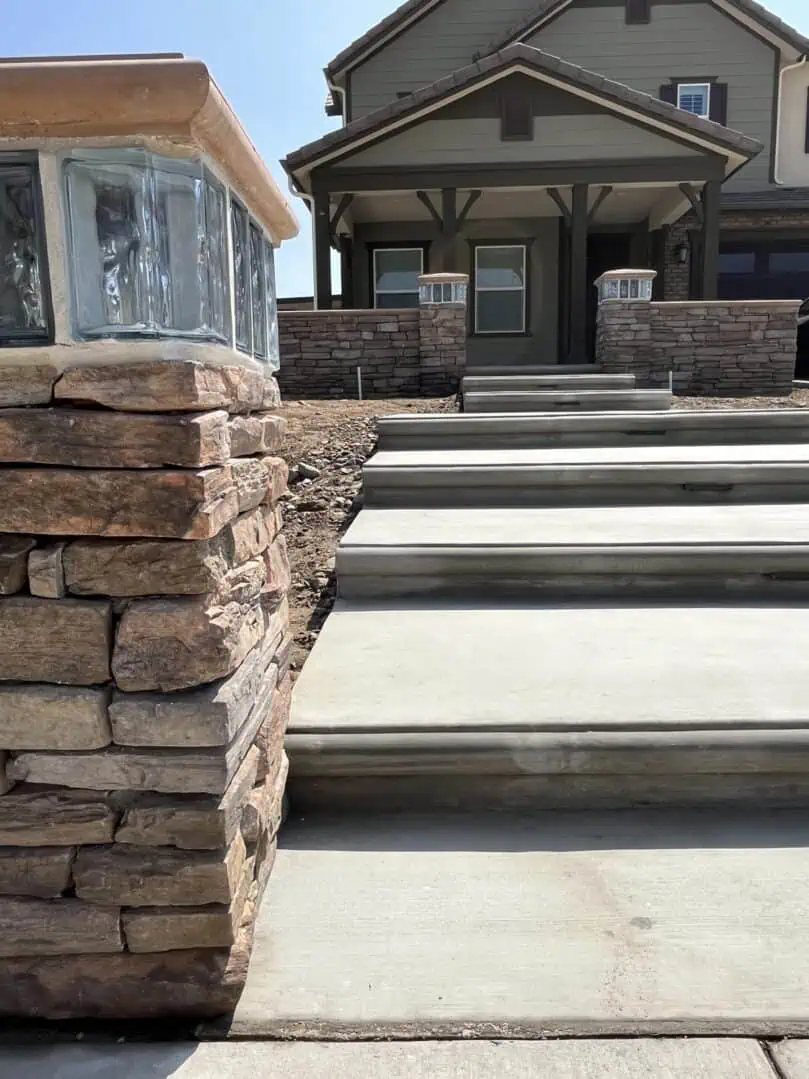 A stone wall with steps leading to the front of a house.