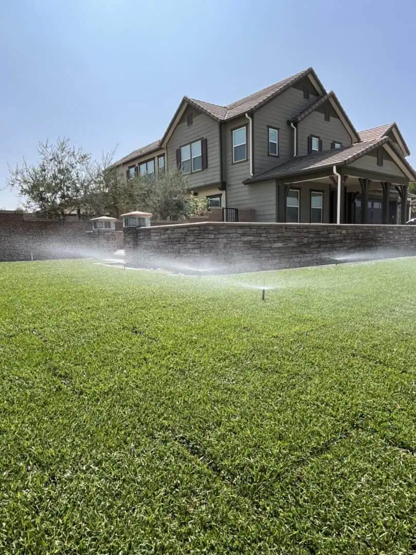 A house with sprinklers spraying water on it.