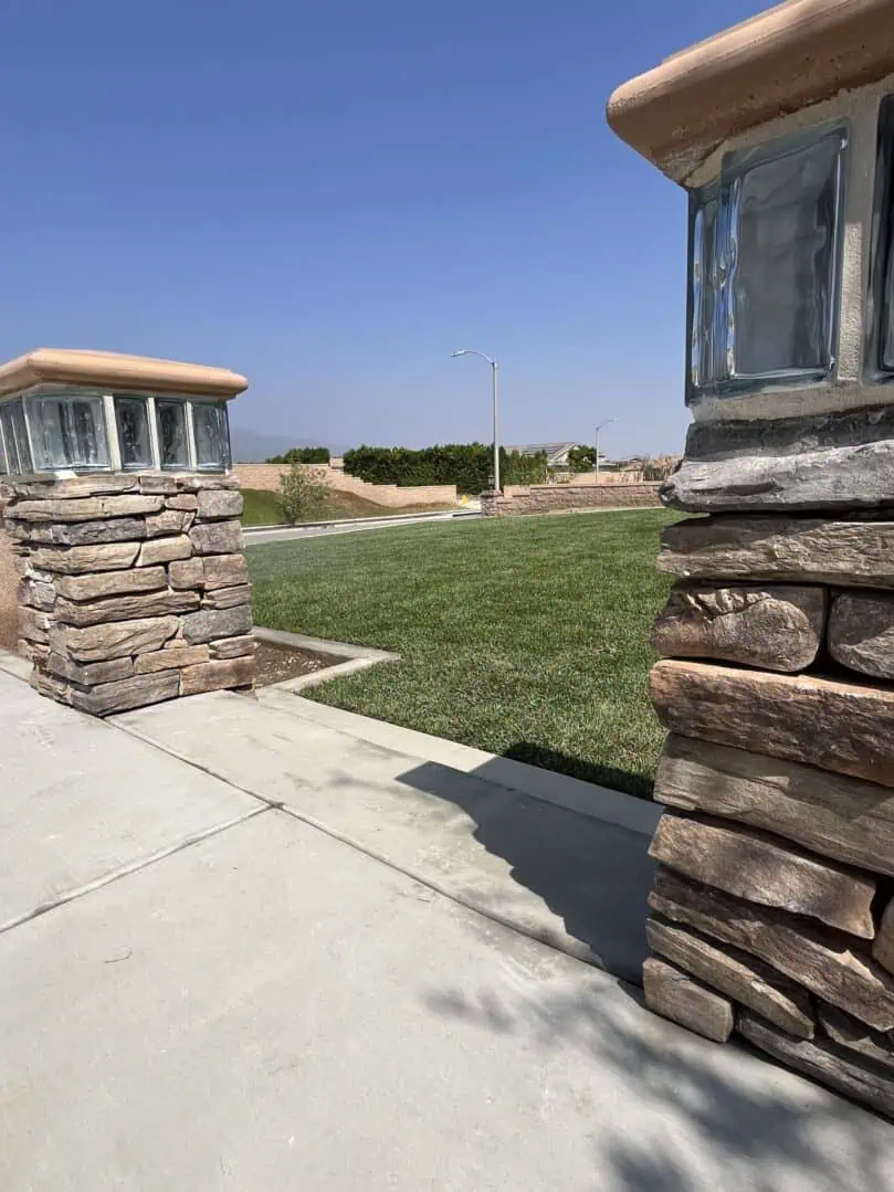 A stone wall and pillars in the middle of an open field.