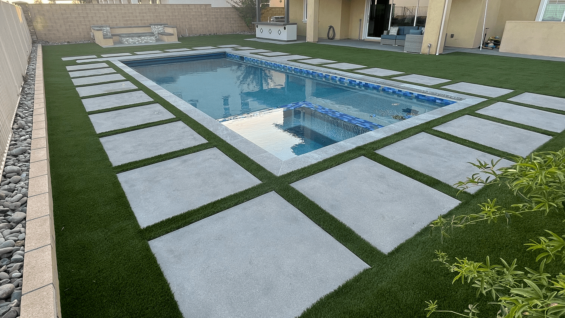 A pool with grass and tiles in the middle of it