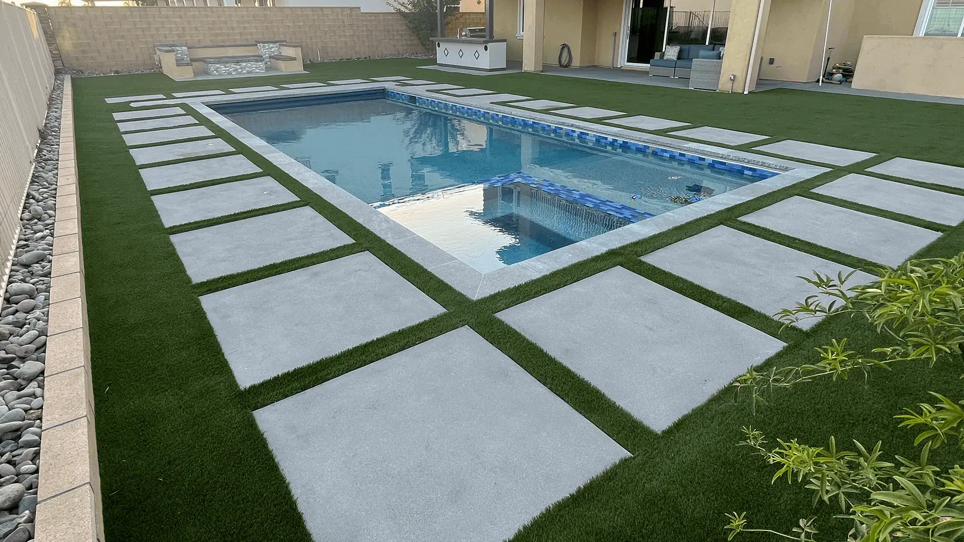 A pool with grass and tiles in the middle of it