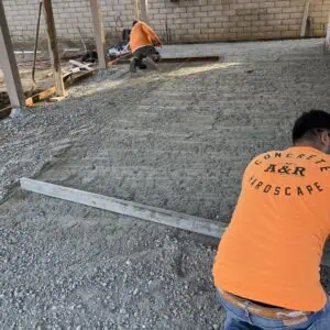 Workers preparing a gravel surface outdoors.