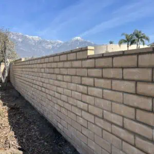 Long brick wall with a clear sky and mountains in the background.