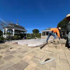Worker installing pavers outdoors on a sunny day.
