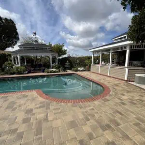 A serene backyard pool area with gazebo and covered patio under a cloudy sky.