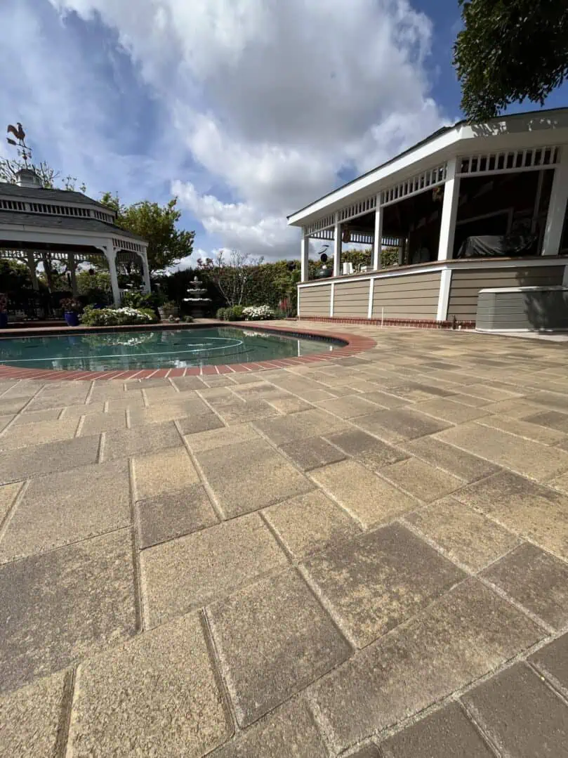 Patio with pool and gazebo under clouds.